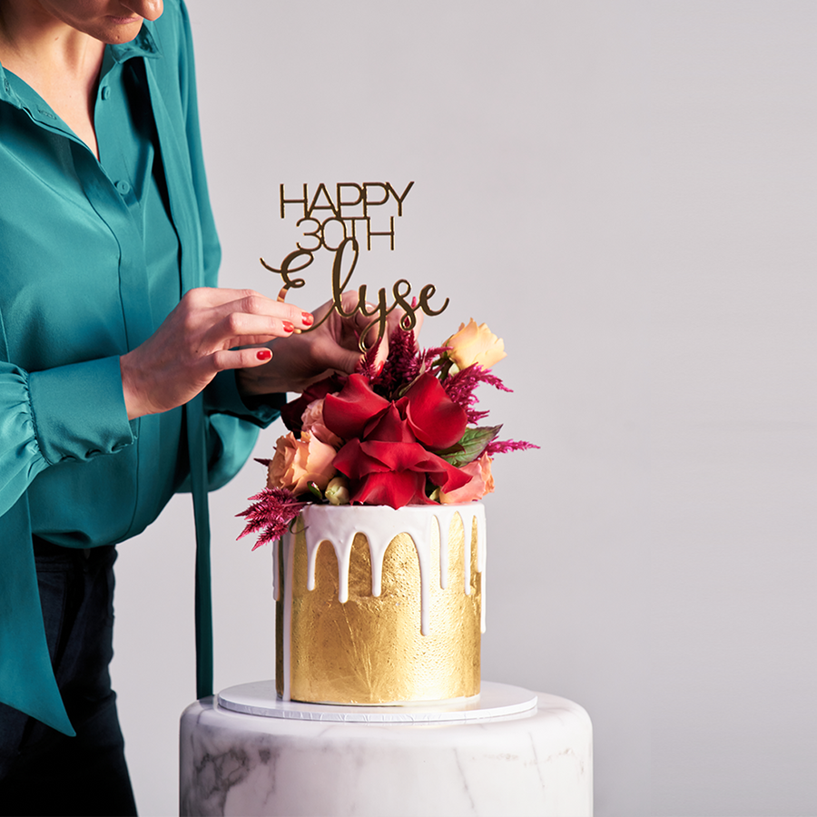 Elegant 23ct gold cake with white drip and vibrant fresh florals