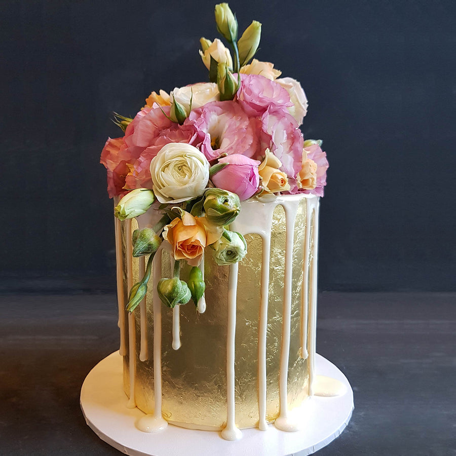 Elegant 23ct gold cake with white drip and fresh florals
