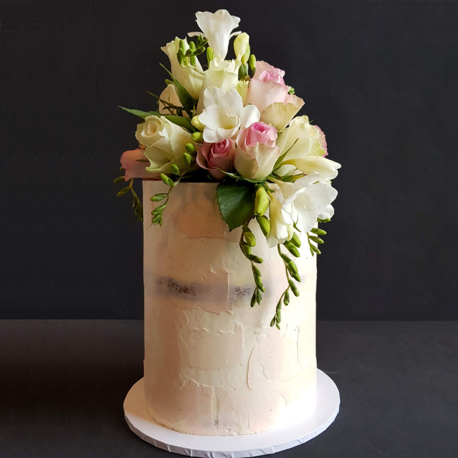 Naked look buttercream cake with smudges of pale pink and fresh florals