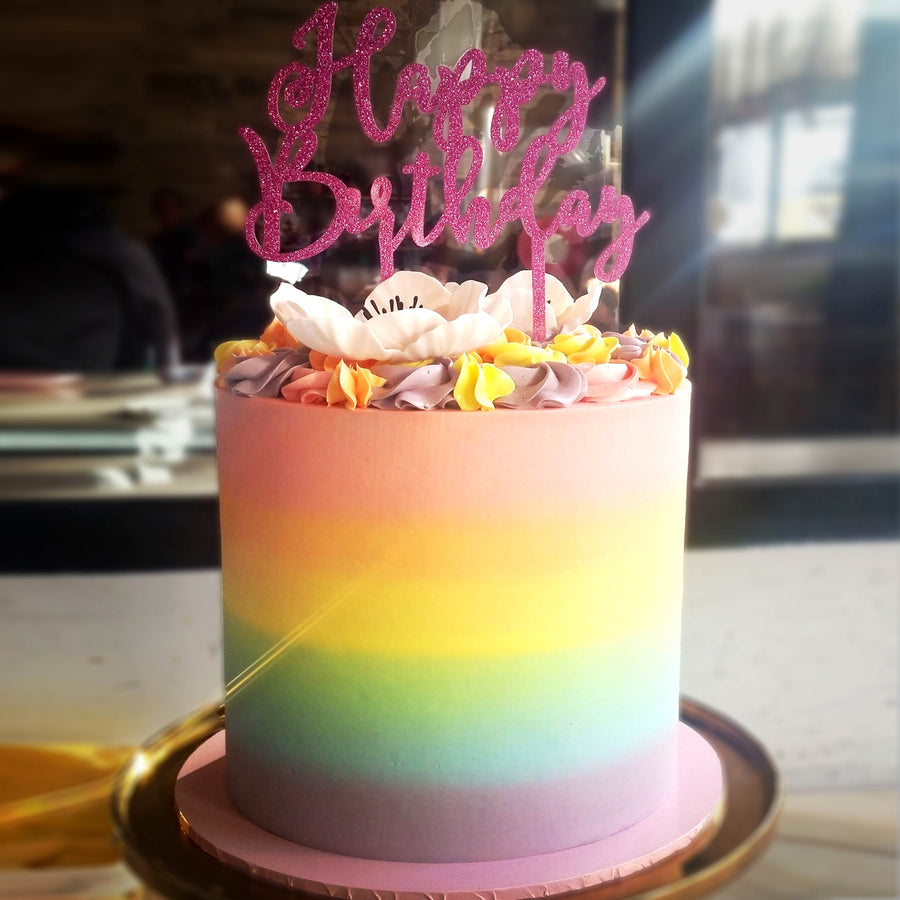 Rainbow buttercream cake topped with buttercream swirls